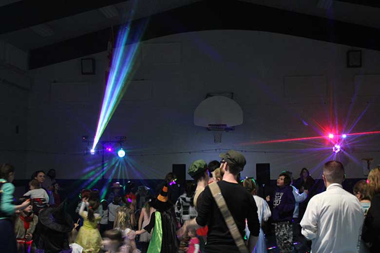 School Light Show, DJ Hamilton, Family Dance light show in background parents holding babies and dancing. Taken in Hamilton Ontario.